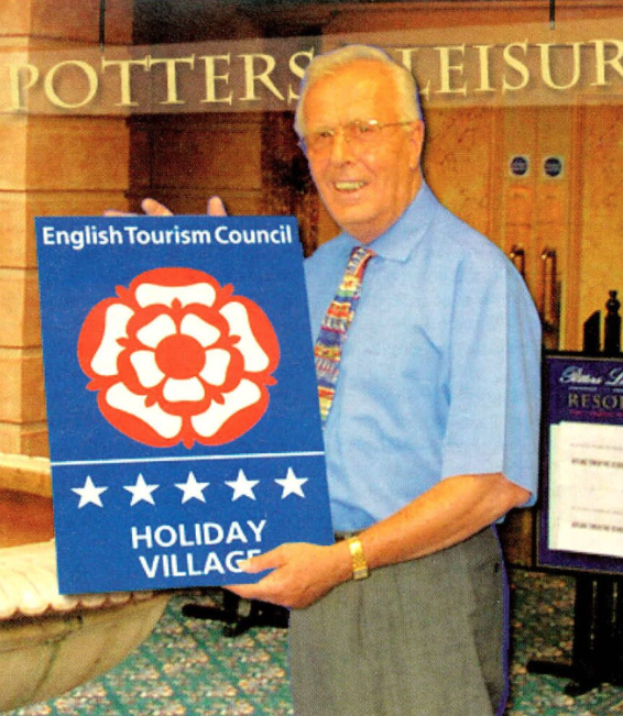 Brian Potter MBE with a sign for the UK's first Five Star Holiday Village in 2003